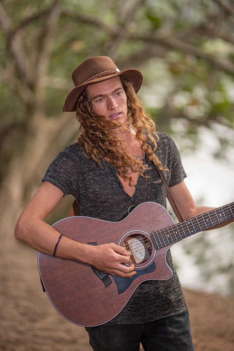 Kauai male model Steven Sedalia at the river, thoughtful, working out chords for new song