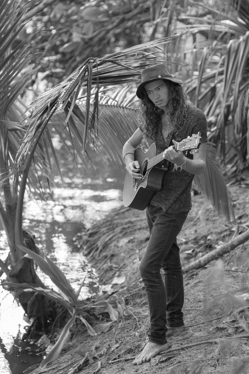 Kauai male model Steven Sedalia playing new song at river's edge. 