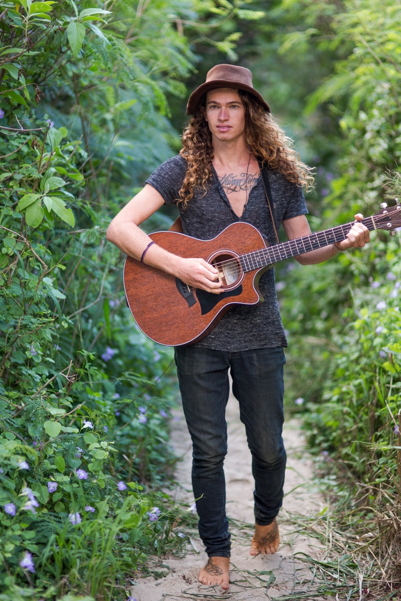 Kauai model Steven Sedalia on jungle path strumming guitar